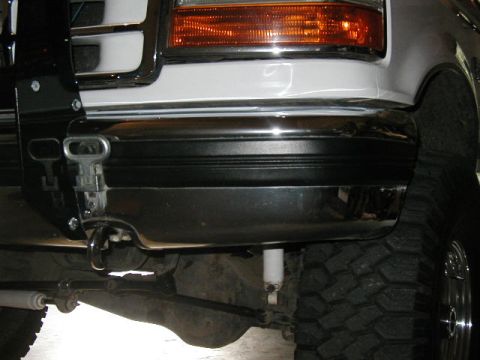 1995 Ford Bronco - Close-up view of the front bumper and tire of a white vehicle, showing aftermarket modifications.