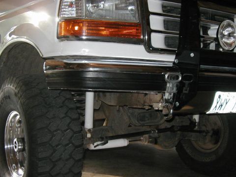 1995 Ford Bronco - Front view of a white Ford truck's bumper and suspension system, with a visible license plate.