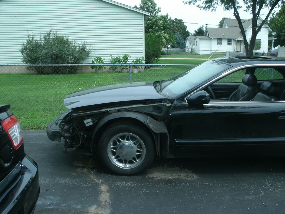 black coupe, front end missing parts, parked next to another car
