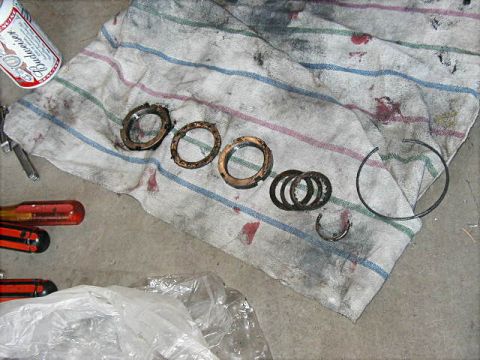 1995 Ford Bronco - Several metal rings and a snap ring are laid out on a stained rag, with tools and a beverage can nearby.