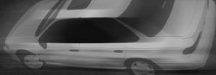 1993 Ford Taurus - A white 1993 Ford Taurus sedan is captured in a motion blur from a 3/4 front perspective, revealing its side profile and roof.