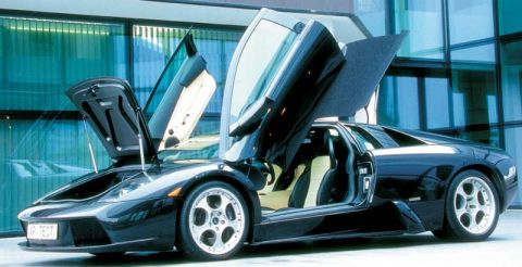 1998 Ford Crown Victoria - A black Lamborghini with its distinctive scissor doors and front hood open, parked in front of a modern glass building.