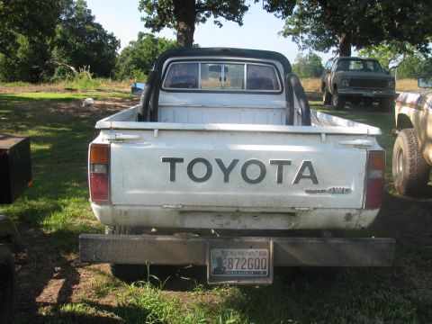 1985 Ford Bronco - A white Toyota pickup truck is parked outdoors, with other vehicles visible in the background.