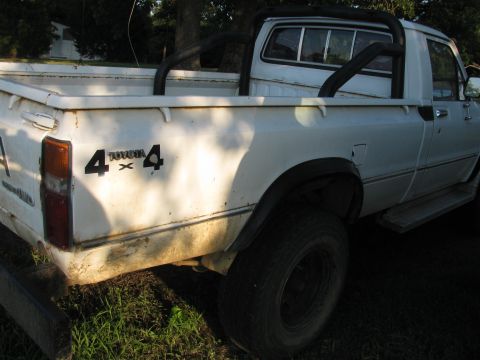 1985 Ford Bronco - This is a white Toyota 4x4 pickup truck, seen from the rear quarter. It has a roll bar.