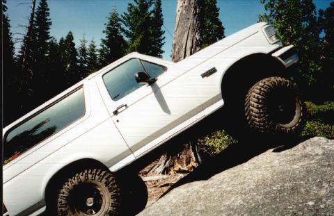 1996 Ford Bronco - A white Ford Bronco navigates rocky terrain with its off-road tires.