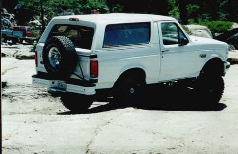 1996 Ford Bronco - This white 1996 Ford Bronco is shown lifted and off-road, with a spare tire mounted on the rear door.