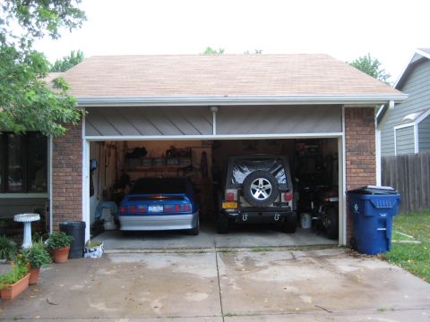 2005 Jeep Wrangler - Two vehicles, a Jeep Wrangler and a blue coupe, are parked inside a garage.