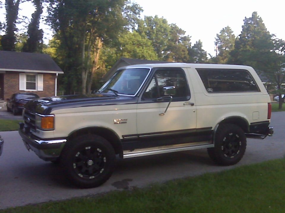 Two-tone Ford Bronco with black hood and white body, parked on a driveway