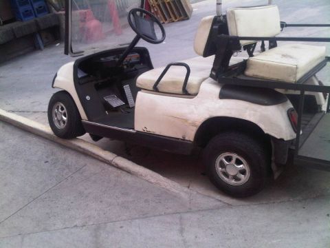 1986 Ford Bronco - This golf cart has a beige body and black trim, with two rows of seating for passengers.