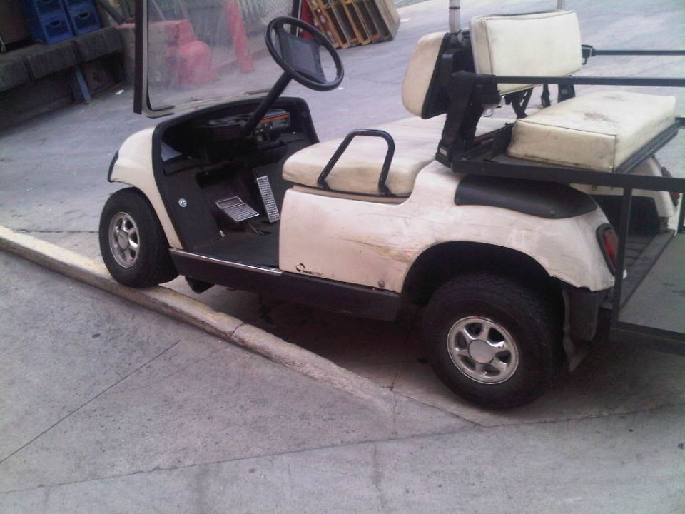 Golf cart with two rows of seats parked on a curb