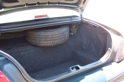 2001 Ford Crown Victoria - The open trunk of a vehicle reveals a spare tire and the interior lining.