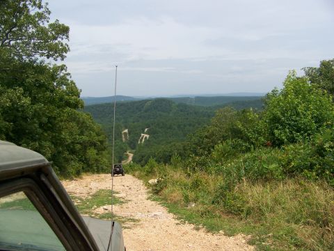 1992 Jeep YJ - A 1992 Jeep YJ navigates a dirt road through a lush, forested mountain landscape.