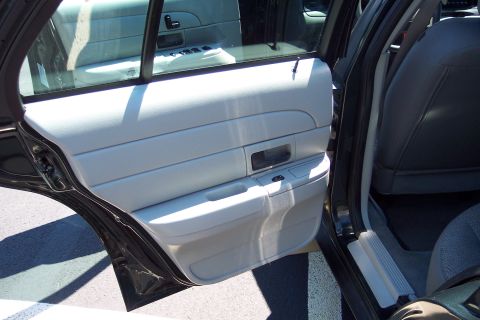 2001 Ford Crown Victoria - Close-up of the interior door panel and seat of a vehicle, with the door ajar.