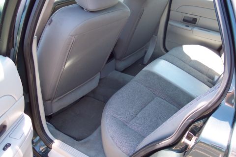 2001 Ford Crown Victoria - Interior view of the back seat area of a car, with grey fabric seats and floor mats visible.