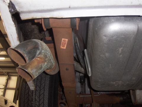 1979 Chevrolet Camaro - Underside view of a vehicle's suspension system, showing a leaf spring and dual exhaust pipes.
