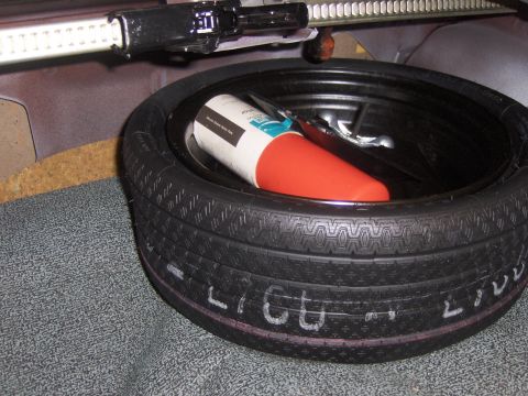 1979 Chevrolet Camaro - Spare tire and jack assembly visible in the trunk of a vehicle, with white lettering on the tire's sidewall.