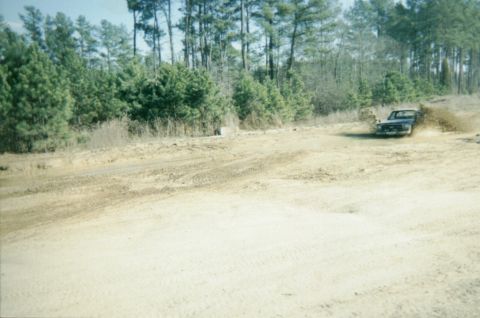 1977 Chevrolet C/K Pickup - A pickup truck navigates a muddy terrain, sending dirt flying.