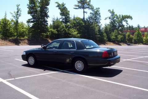 2001 Ford Crown Victoria - Dark green 2001 Ford Crown Victoria parked in a paved lot with trees in the background.