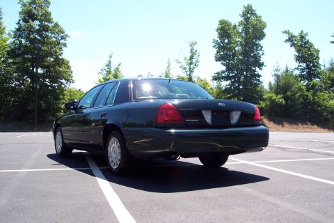 2001 Ford Crown Victoria - Rear view of a dark green 2001 Ford Crown Victoria parked in an empty lot.
