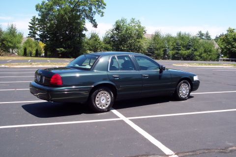 2001 Ford Crown Victoria - Dark green 2001 Ford Crown Victoria parked in an asphalt lot with white lines.