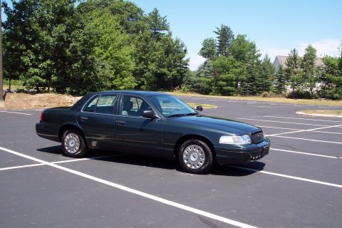 2001 Ford Crown Victoria - A dark green 2001 Ford Crown Victoria is shown from a three-quarter front view in an empty parking lot.