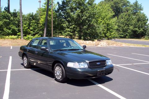 2001 Ford Crown Victoria - 2001 Ford Crown Victoria sedan parked in an empty lot with trees in the background.