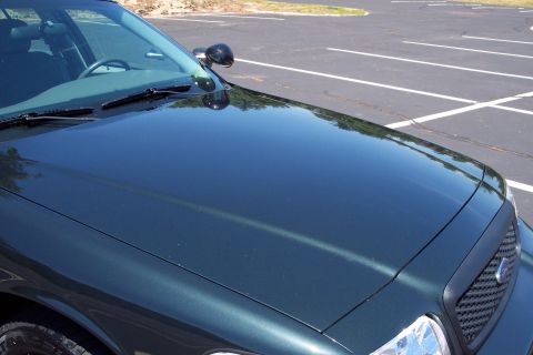 2001 Ford Crown Victoria - A dark green police car is viewed from the front, showing its hood, grille, and windshield.