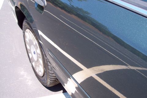 2001 Ford Crown Victoria - A dark green 2001 Ford Crown Victoria is viewed from the side, highlighting its rear door and wheel.