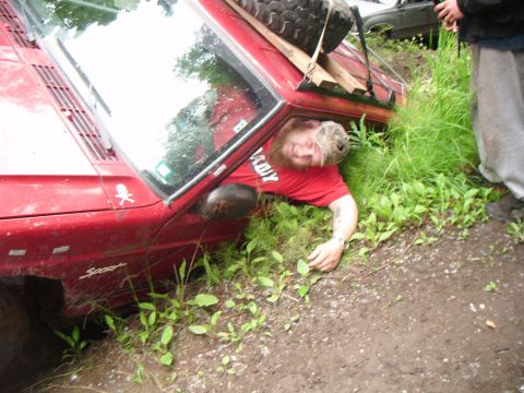 1998 Jeep Cherokee - Man is stuck in a red 1998 Jeep Cherokee that has overturned off the side of the road.