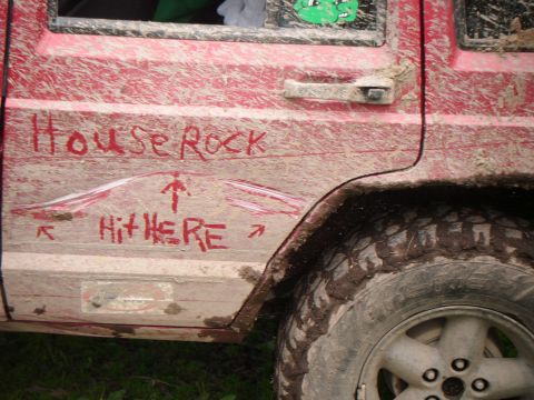 1998 Jeep Cherokee - Mud-splattered 1998 Jeep Cherokee side panel shows graffiti and off-road damage.
