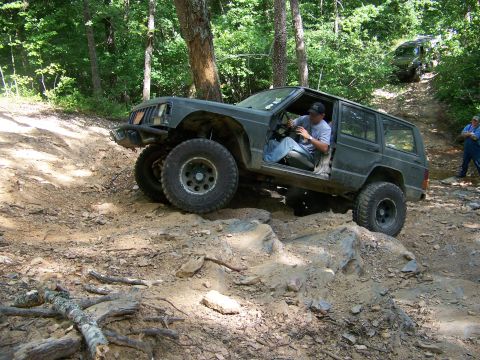 1992 Jeep YJ - Two Jeep Cherokees navigate a challenging off-road course in a wooded area.