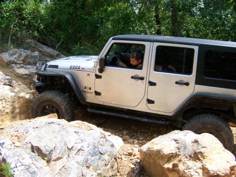 1992 Jeep YJ - A Jeep Wrangler navigates a rocky off-road trail with a driver behind the wheel.