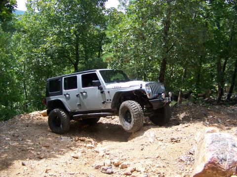 1992 Jeep YJ - A silver Jeep Wrangler navigates a rocky, wooded trail.