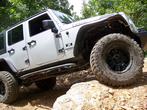 1992 Jeep YJ - White Jeep Wrangler Unlimited navigates a rocky trail with aggressive off-road tires.