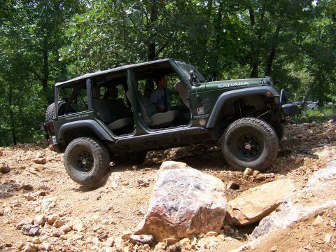 1992 Jeep YJ - A green Jeep Wrangler Sahara navigates a rocky off-road trail with its doors removed.