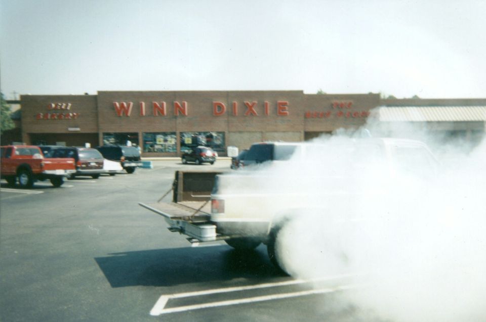 Pickup doing a burnout in a Winn-Dixie parking lot, rear end hidden in tire smoke