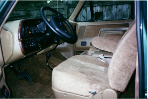 1990 Ford Bronco - The interior of this vehicle features tan cloth seats and a wood-grain trim on the dashboard.