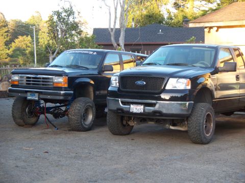 1977 Ford F-150 - A black Ford F-150, likely from the mid-2000s, is parked next to a lifted Ford Explorer.