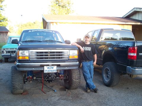 1977 Ford F-150 - A man poses with a modified black Ford Explorer, with a green Ford truck visible in the background.