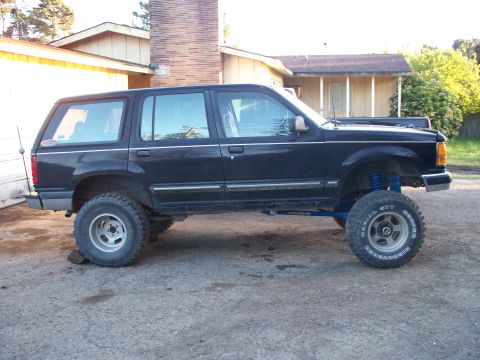 1977 Ford F-150 - This lifted SUV features large off-road tires and prominent blue suspension parts, suggesting significant modifications.