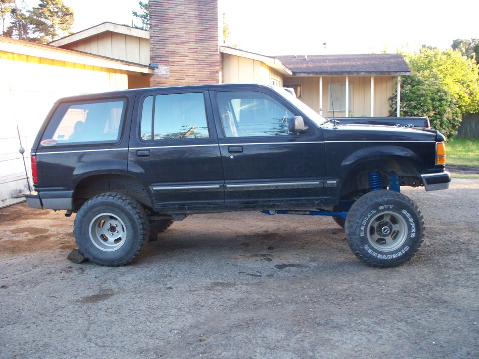 Black lifted SUV with off-road tires and blue suspension components
