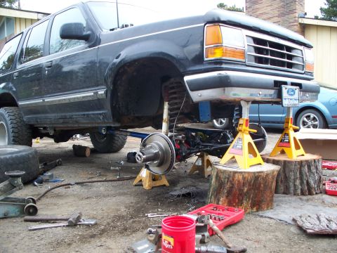 1977 Ford F-150 - Front suspension of a black Ford Explorer is being worked on, with the vehicle supported by jack stands.