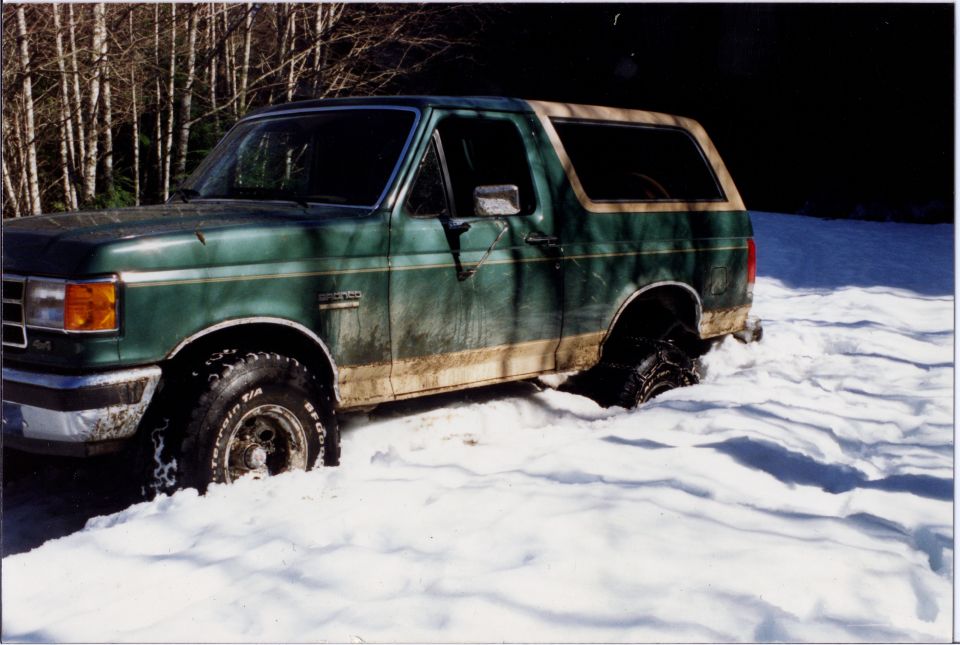 Green 1990 Ford Bronco stuck in deep snow, tires deep