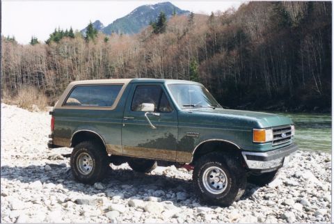 1990 Ford Bronco - This 1990 Ford Bronco is parked on a rocky riverbank with a wooded mountainside behind it.