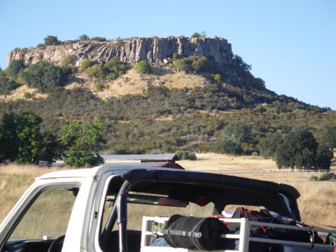 1991 Ford Bronco - A white Ford Bronco is parked in a dry, grassy field with a large rock formation in the background.