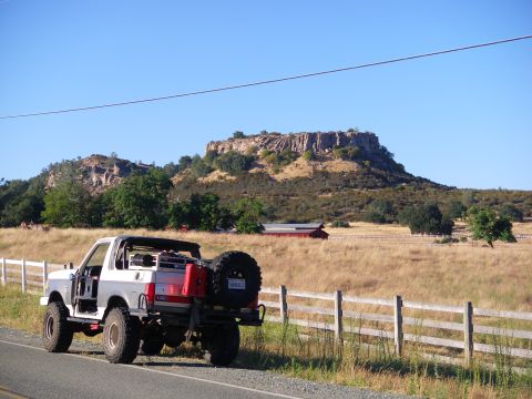 1991 Ford Bronco - A 1991 Ford Bronco is parked on the side of a road with a scenic landscape in the background.