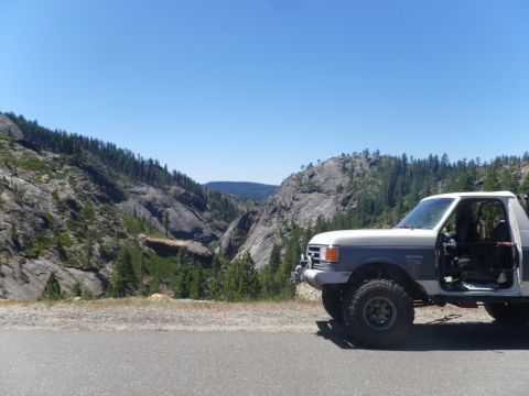 1991 Ford Bronco - A 1991 Ford Bronco is parked roadside, offering a view of the mountainous terrain and clear blue sky.