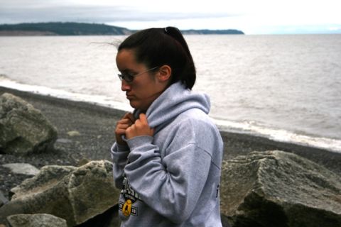 1990 Chevrolet Suburban - Woman on a rocky beach with the ocean and a distant shoreline in the background.