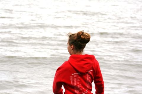 1990 Chevrolet Suburban - A person in a red hoodie stands by the water, with text printed on the back of the garment.