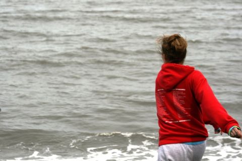 1990 Chevrolet Suburban - A person wearing a red hooded sweatshirt stands by the water, with text printed on the back of the garment.